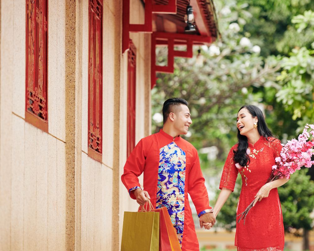 Couple-wearing-traditional-costumes-holding-roses-having-fun-on-New-Year-s-Day