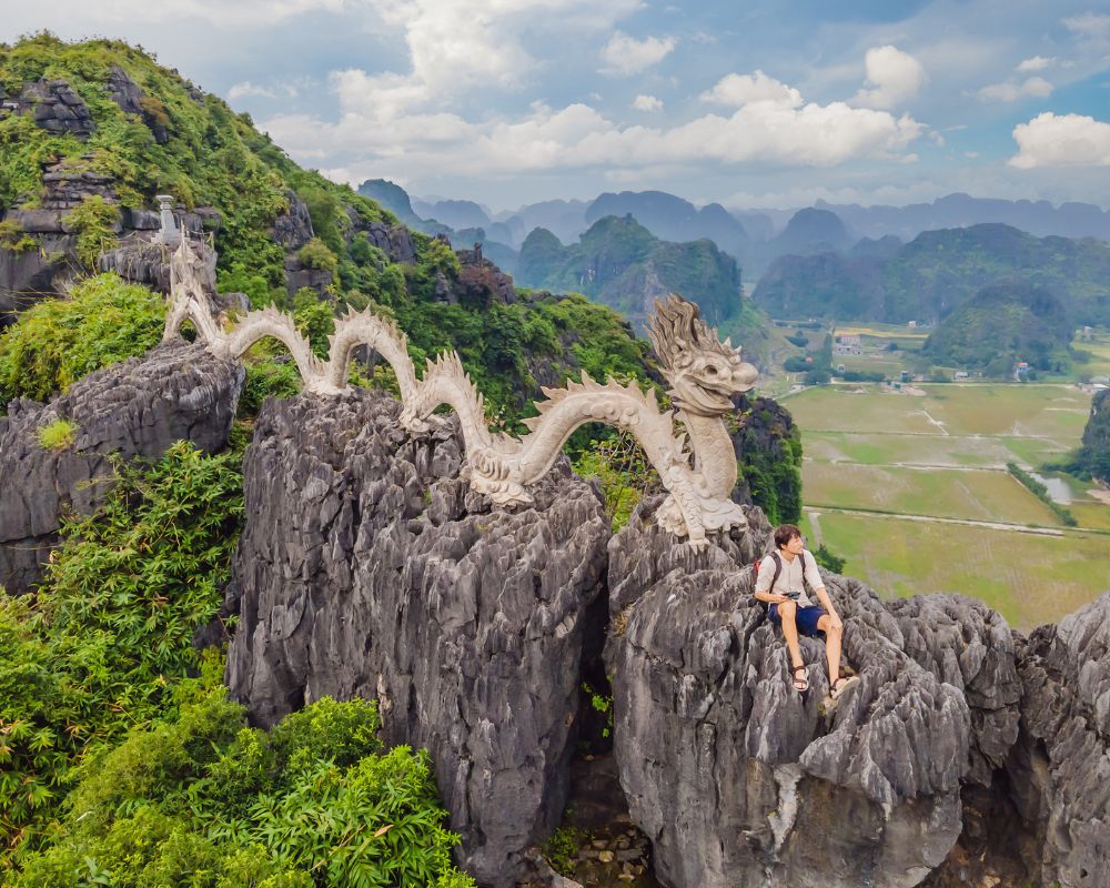Male-tourist-on-the-background-of-amazing-huge-dragon-statue-at-limestone-mountain-top-near-Hang-Mua-Ninh-Binh